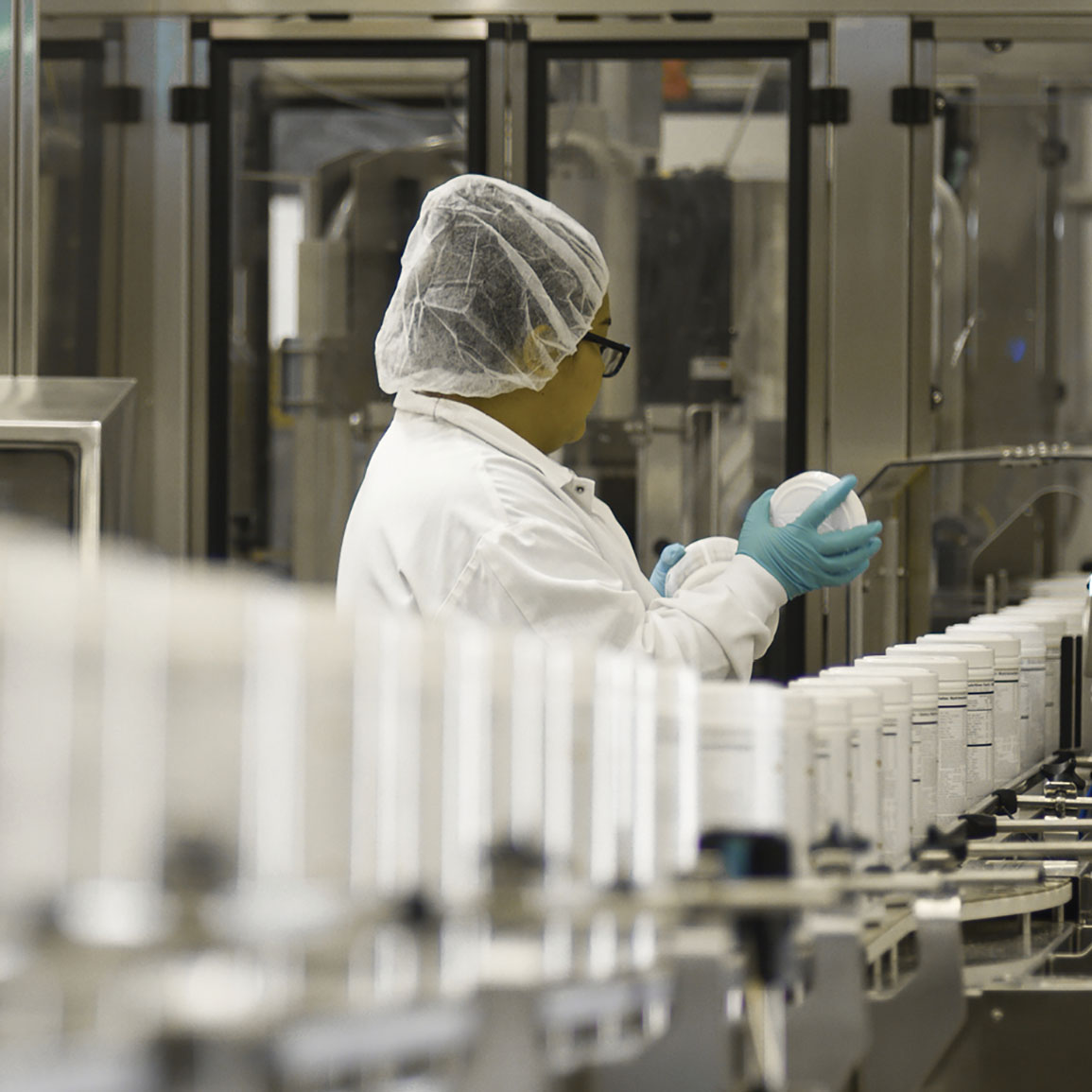 Scientist Checking Formula 1 Shakes On A Conveyor Belt In The Warehouse