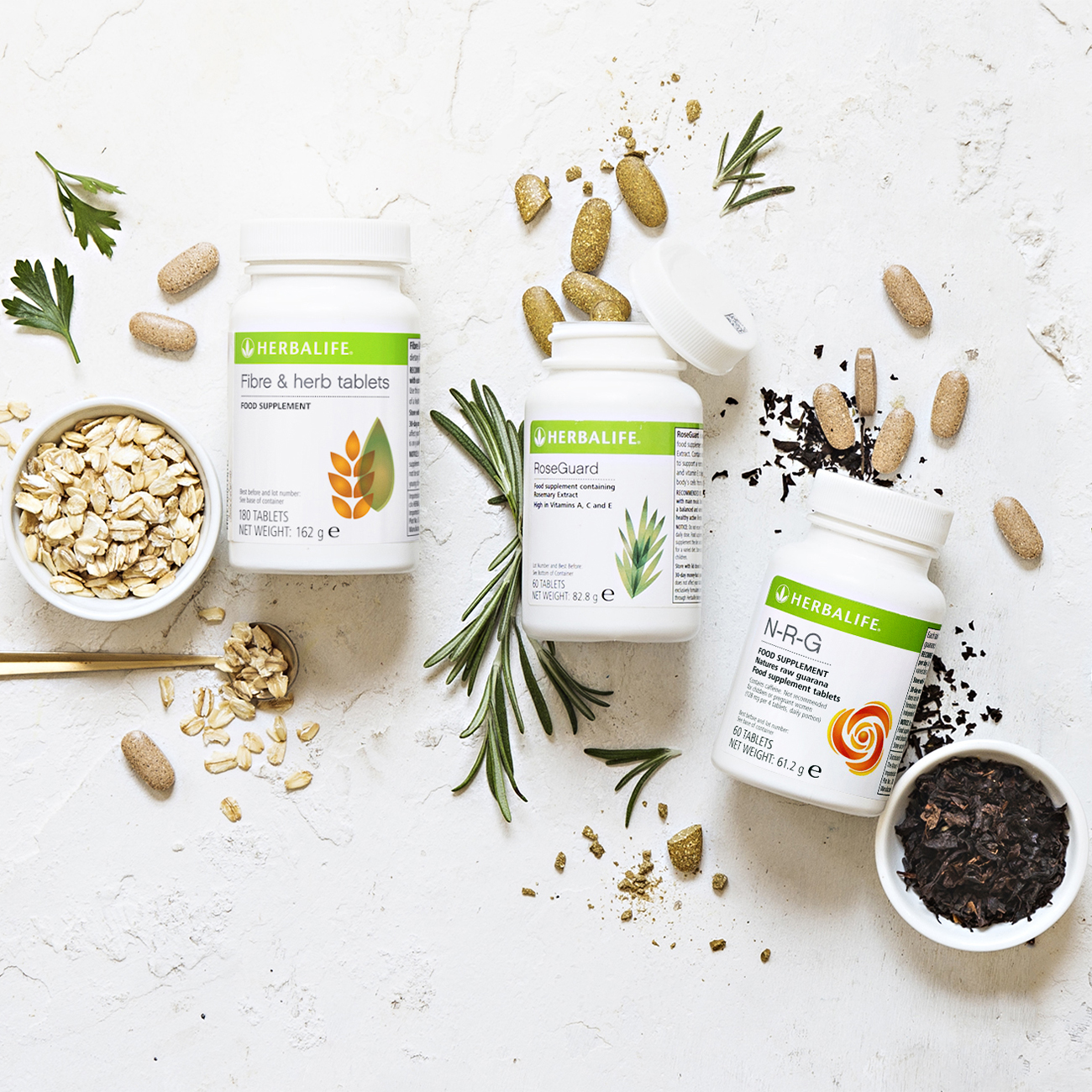 bottles of herbalife nutrition supplements with fibre & herb, roseguard and n-r-g tablets on white table 
